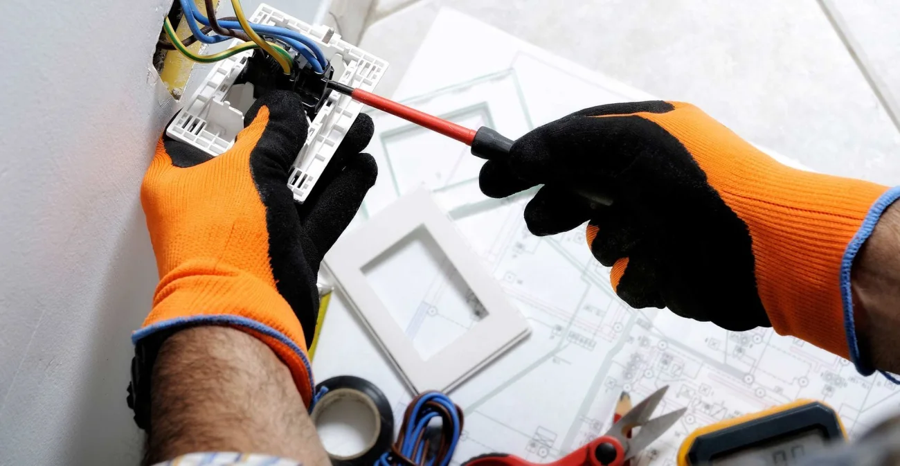 An electrician working on wiring and a control panel