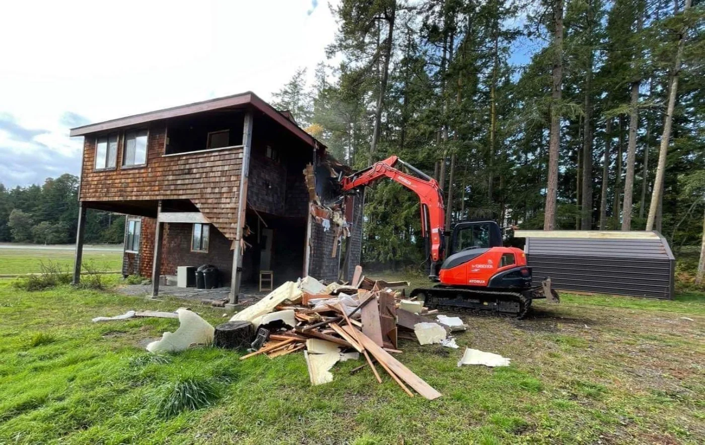 An island home mid-remodel with an excavator on site